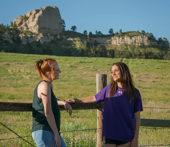 Two people chatting with a butte in the background