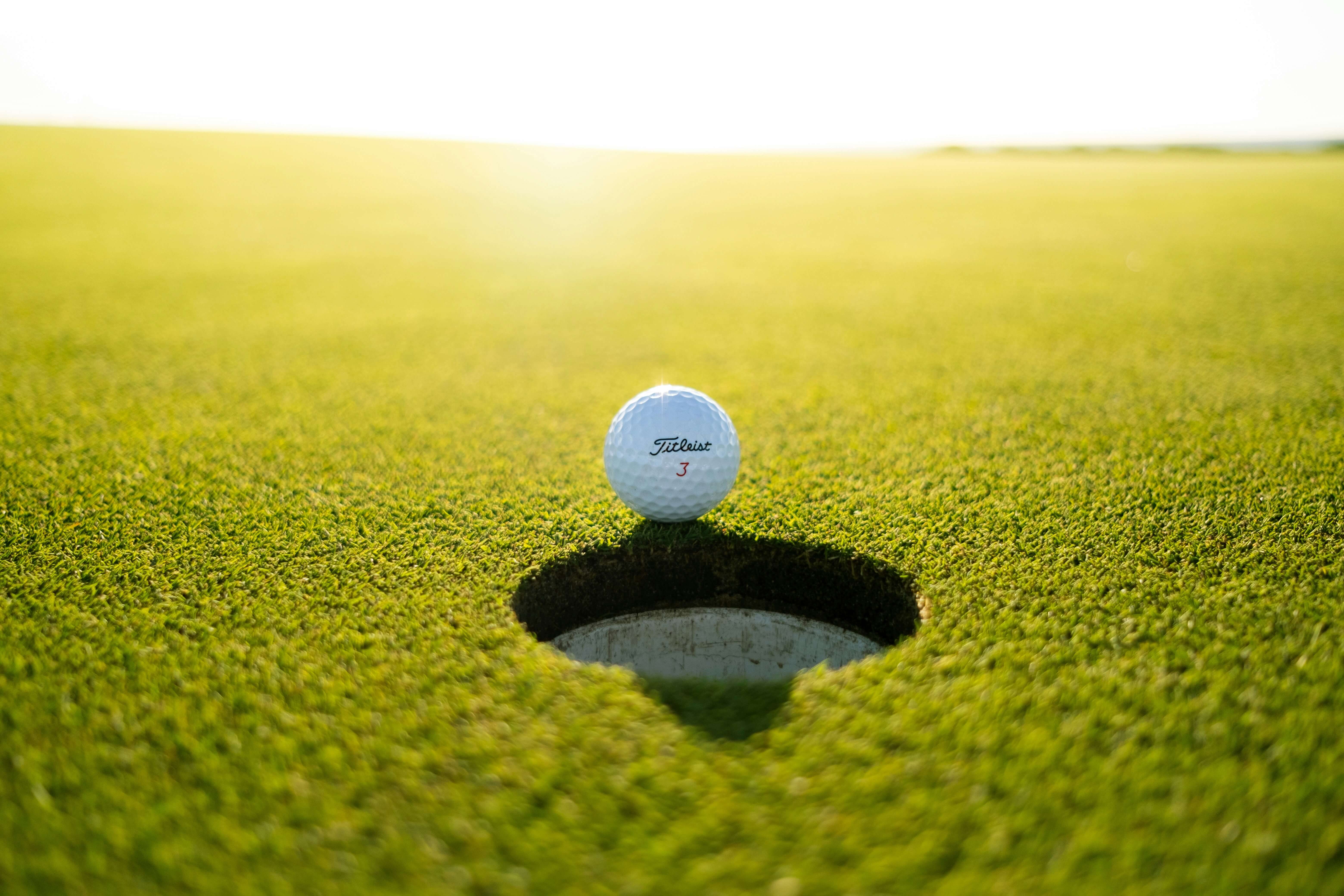 Golf ball sitting on edge of cup