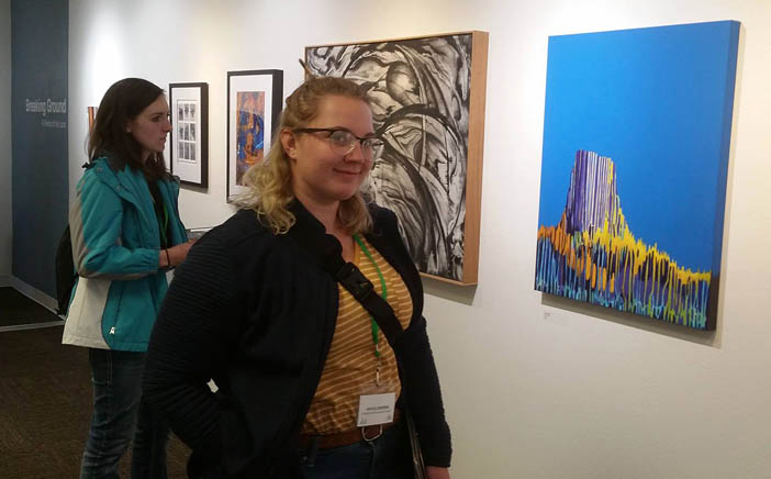 Two students view paintings on a wall