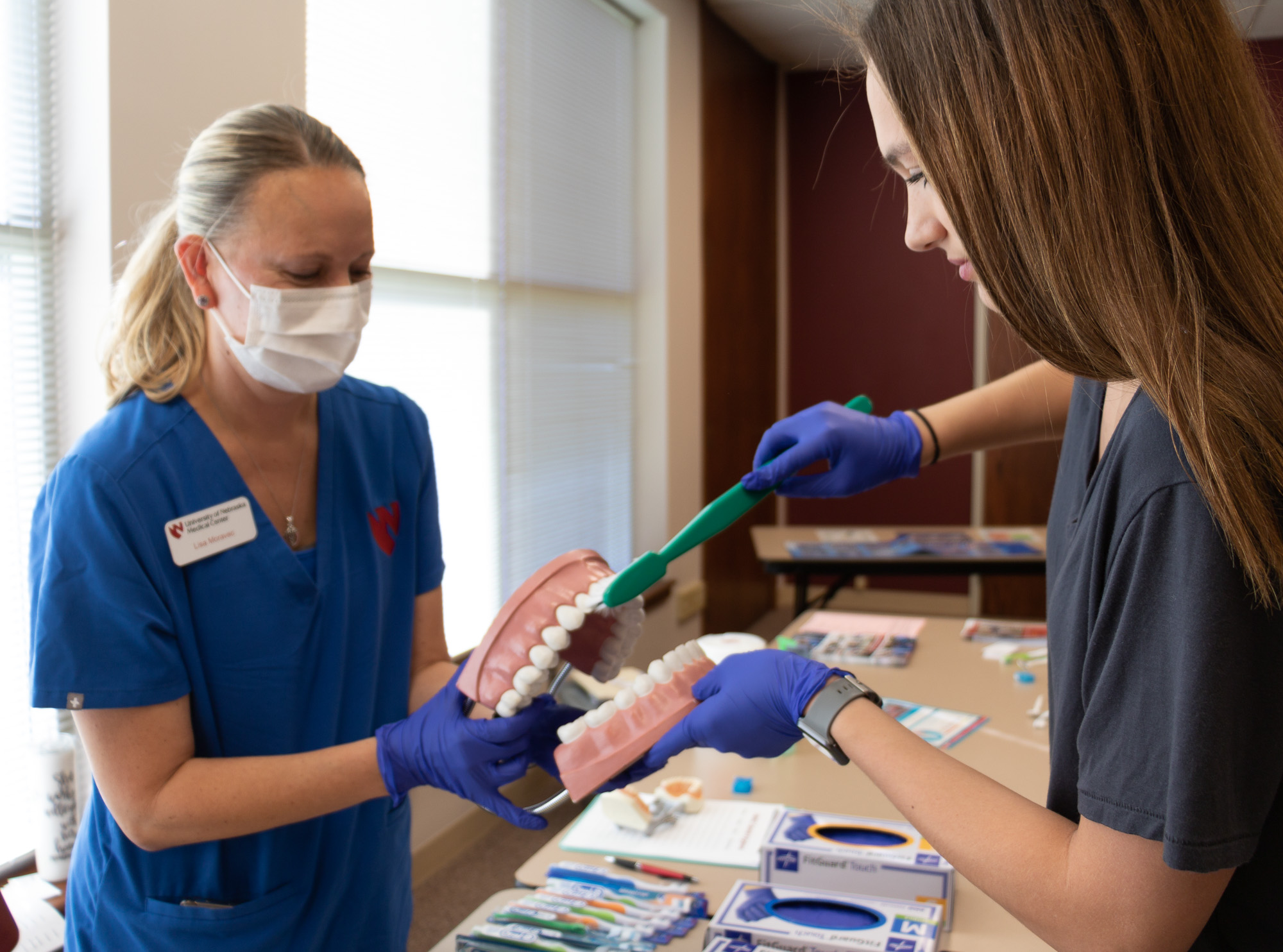 Lisa Moravec demonstrates how to properly brush teeth to a CSC student at the Health Professions Showcase