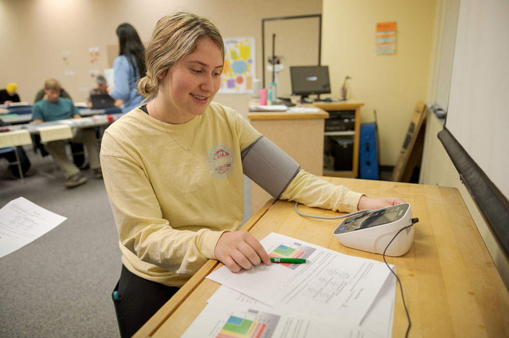 A student takes a blood pressure test in the Burkhiser Complex
