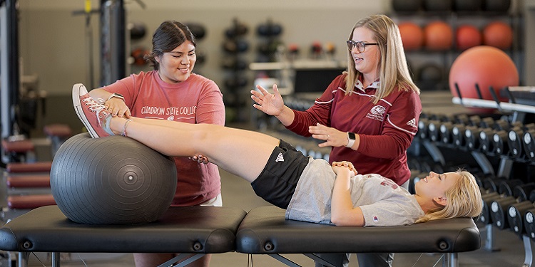 A woman showing teaching a student about athletic training with someone being examined