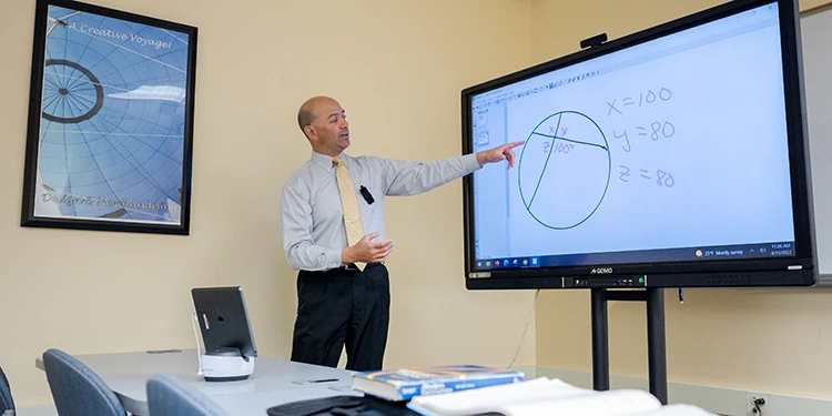 A Teacher doing a math problem on a projected screen