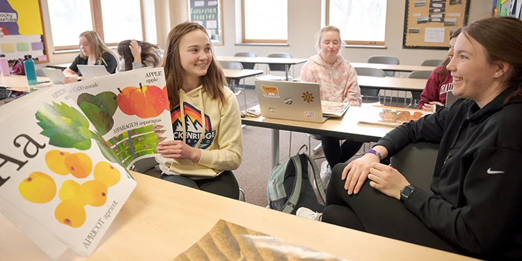 Students in an education class practice reading a large oversized picture book to each other