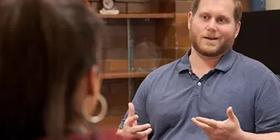 An over the shoulder look from a woman's perspective, with man at a desk talking to her