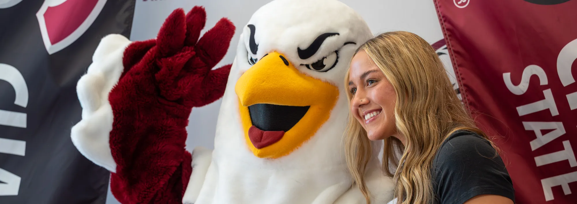 Eagle mascot and student waving and posing for a photo