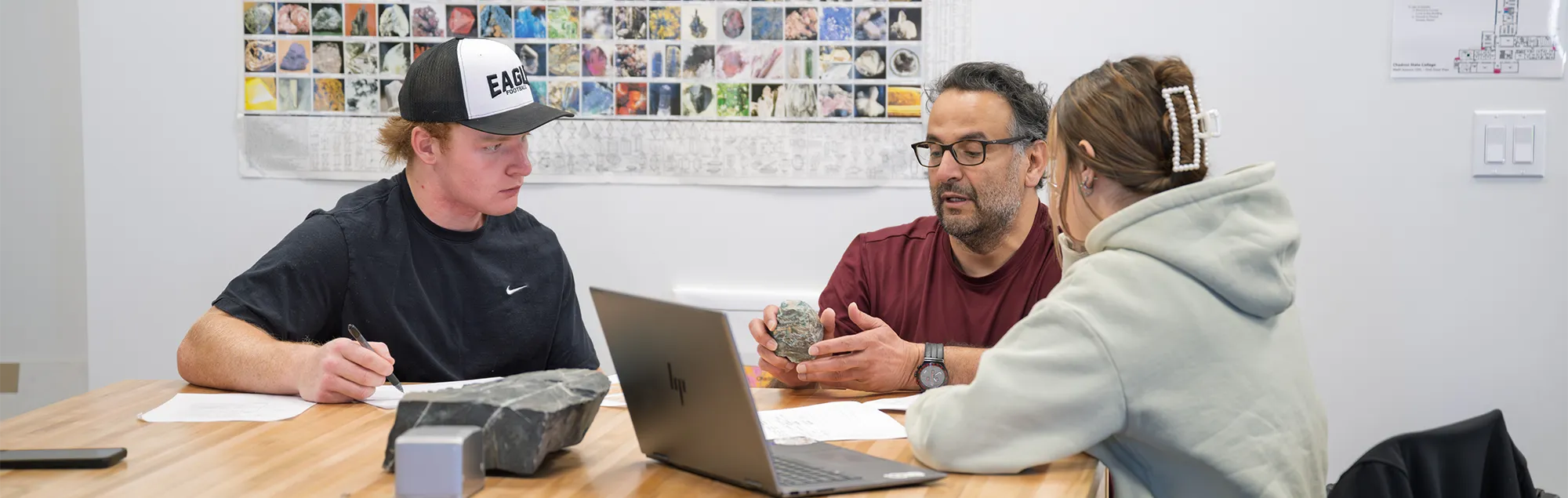 Two students and a Geoscience professor examine a mineral sample