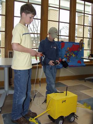 Seventh-grader Garrett Frederick demonstrates the Caterpillar truck he created with help from Chadron State student Jeremiah Vardiman.