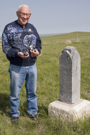 Jim Sheaffer holds a digital camera and GPS unit near a gravestone north of Chadron that was left behind when the rest of a cemetery was moved.