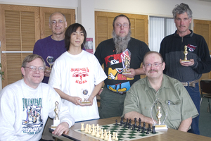 People pose with chess board and awards