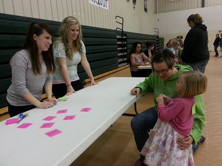 Chadron State College students, from left, Amanda Einspahr of McCook, Nebraska, and Lauren Moller of Alliance, Nebraska, teach Reese Varvel and her mother, Raime Varvel, during the 2014 Hay Springs Family Math Night