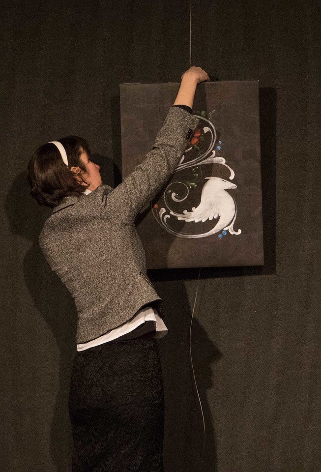 Carly Heath hangs White Horse Rosemaling, a digital illustration on canvas, for the Chadron State College art faculty show,