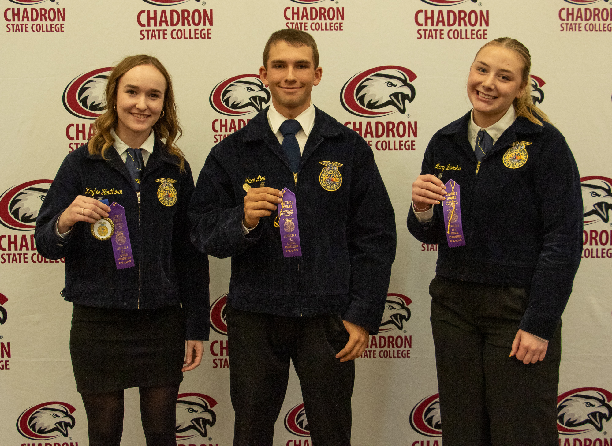 Three students standing with ribbons