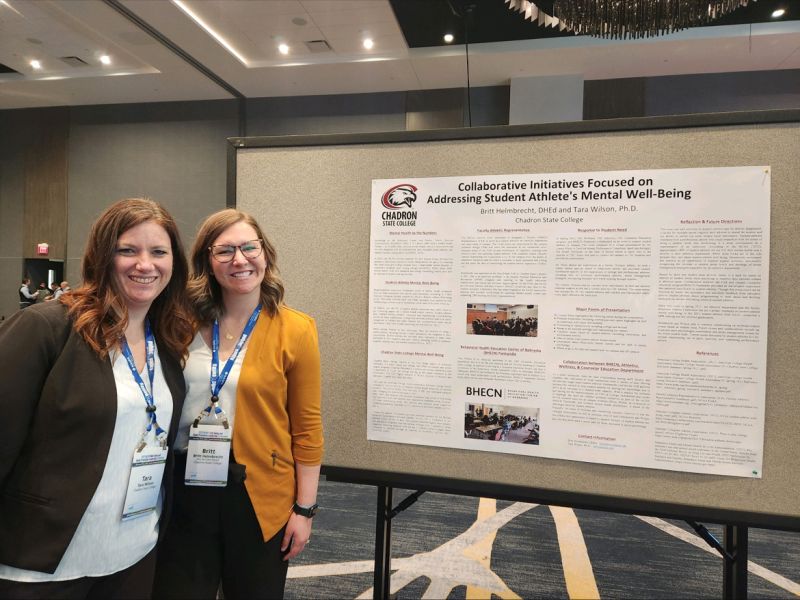 Two women posing by a poster