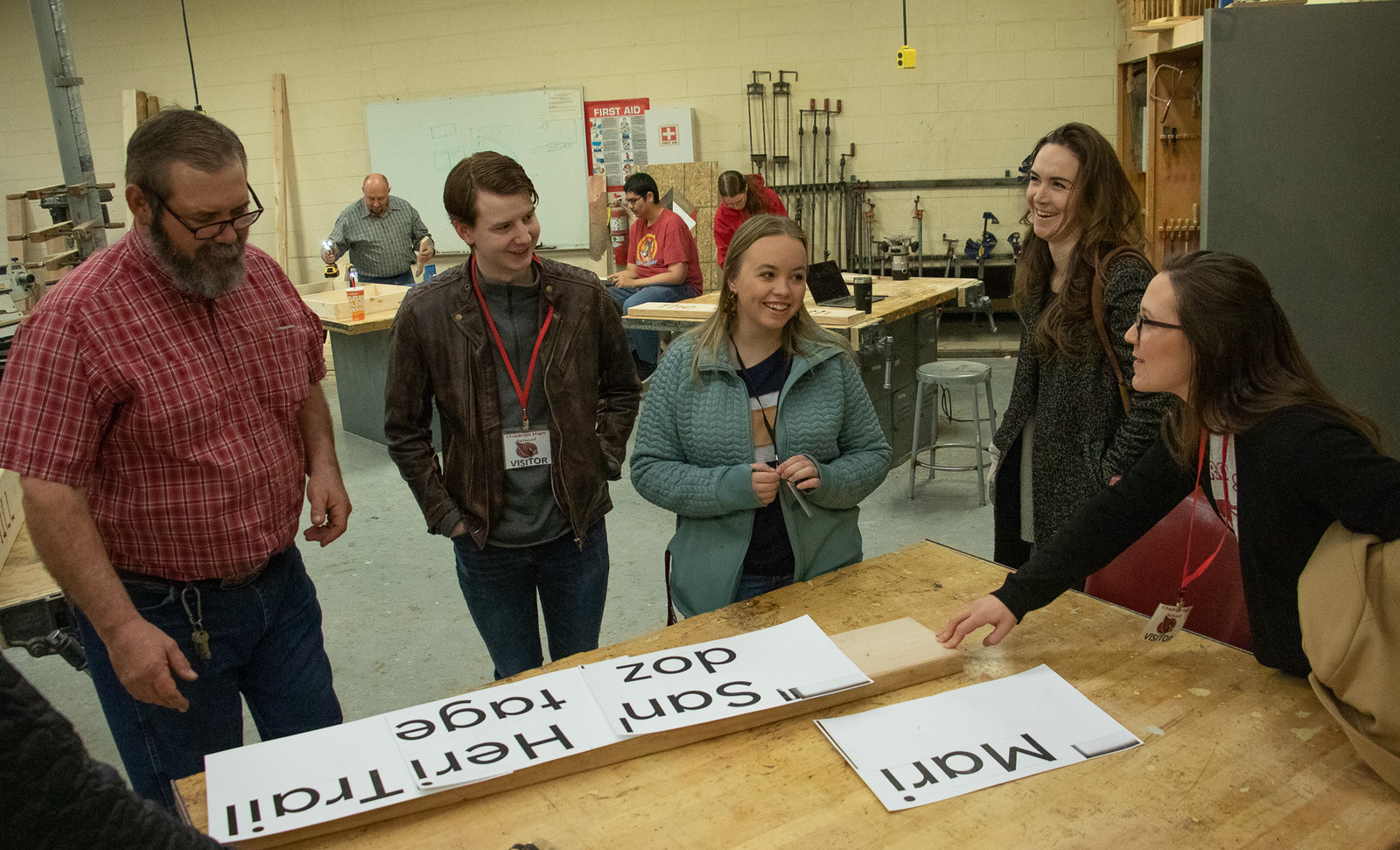 Five people standing by a shop work table