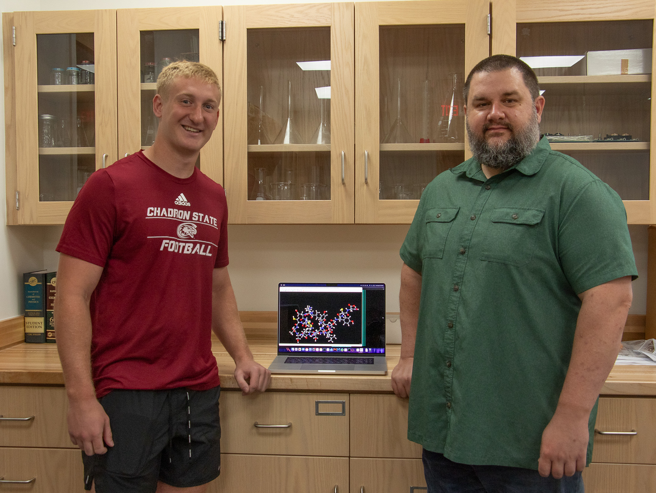 Two men standing in a lab by a laptop