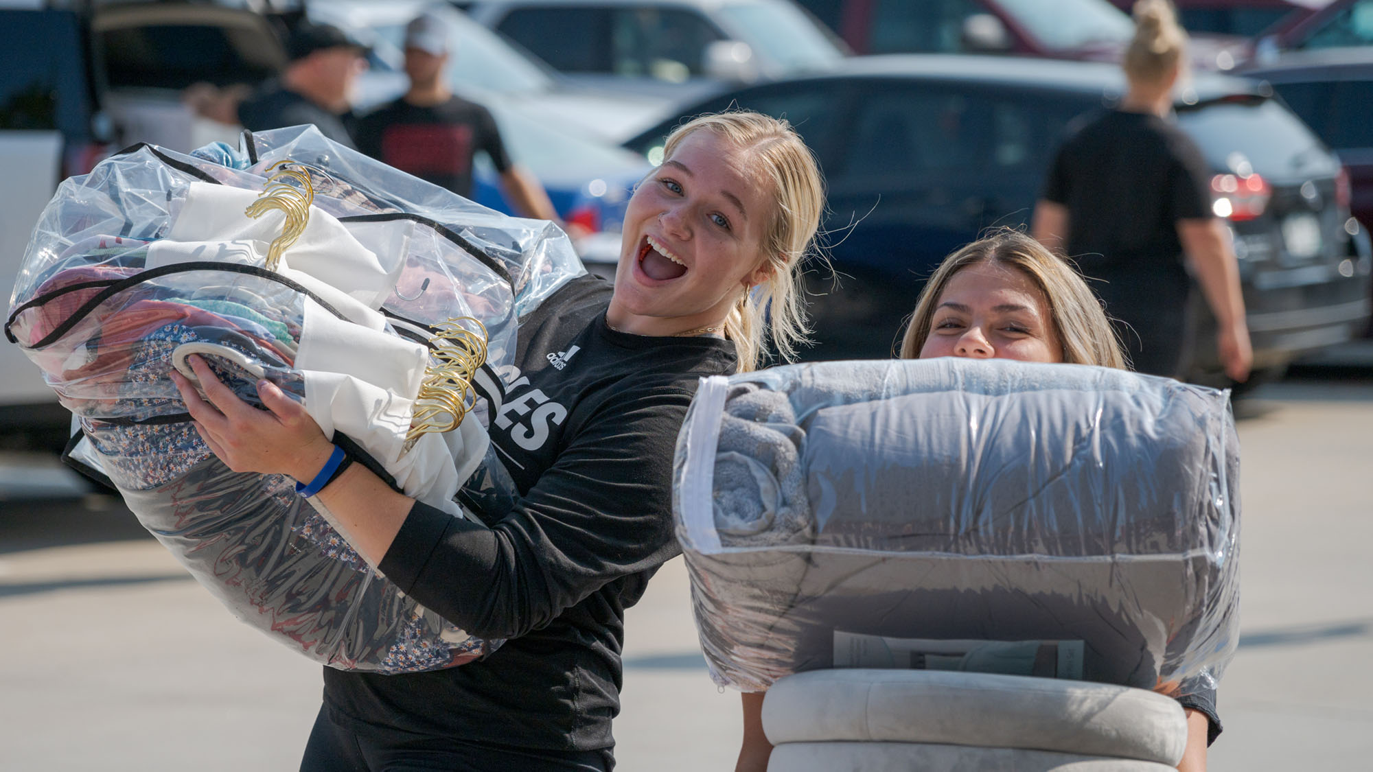 Two students carrying clothing and other items into a residence hall