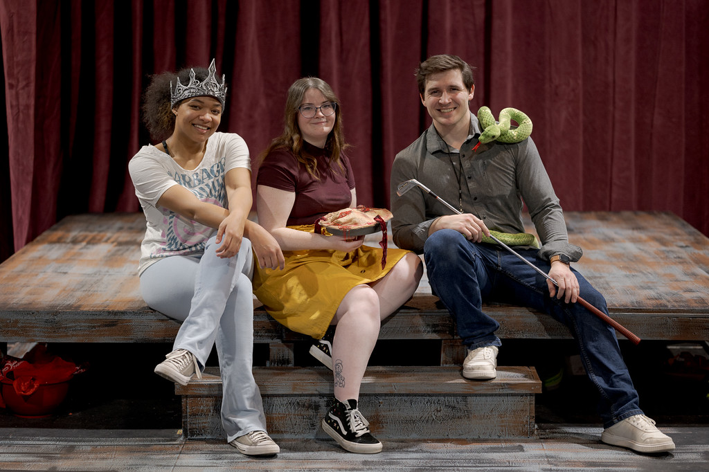 Three actors seated on a stage