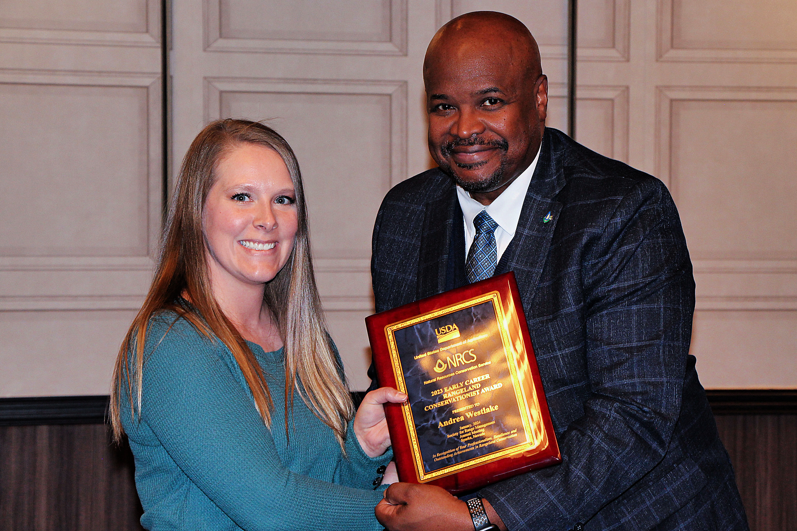 Two adults posing with an award