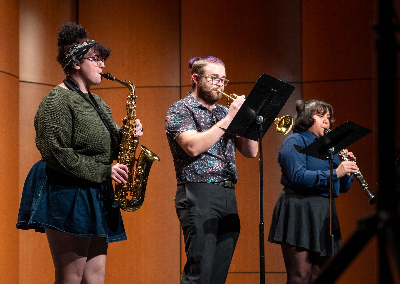 Three students playing musical instruments on stage