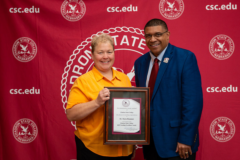 Two adults posing with an award