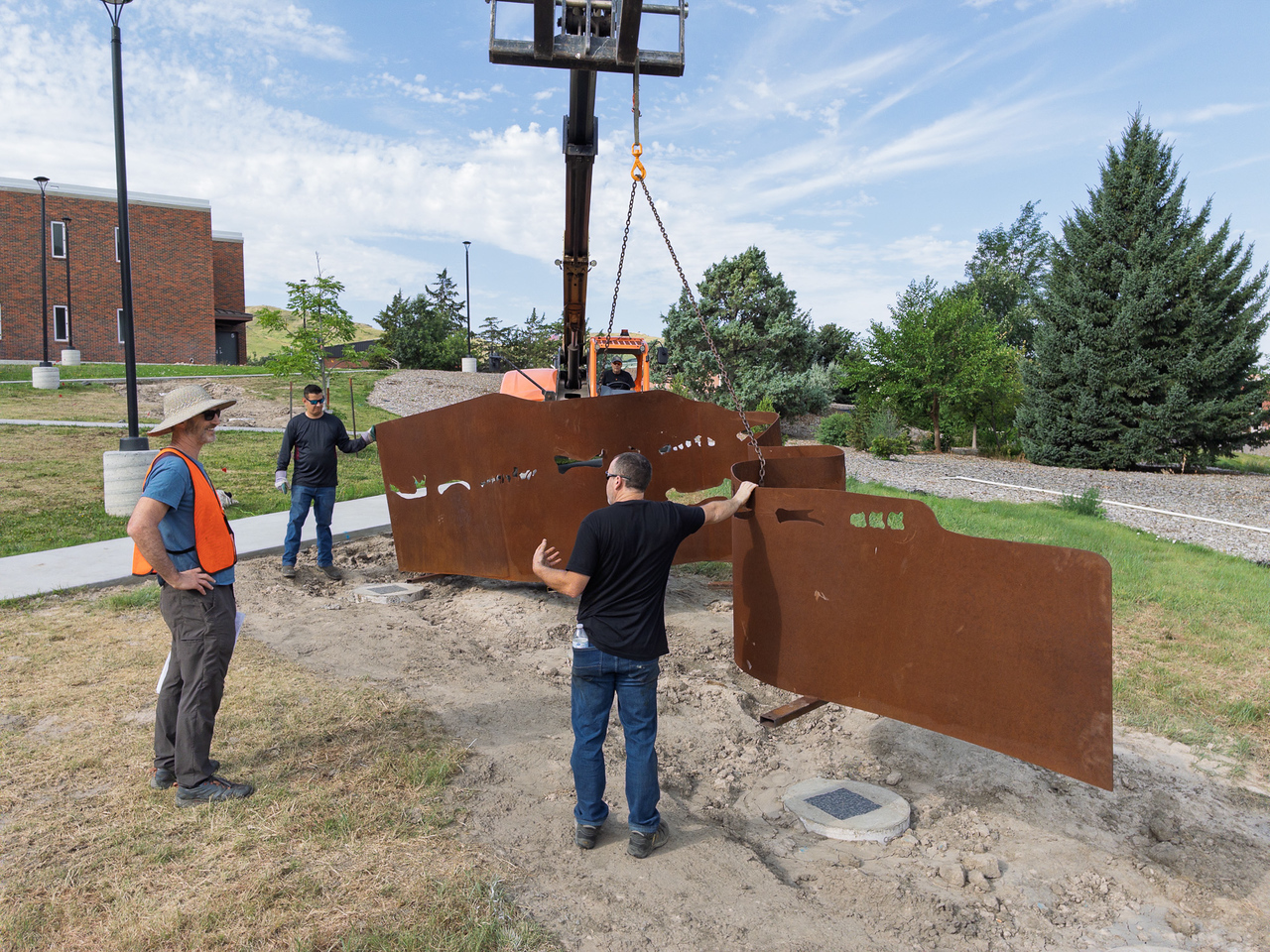 Workers installing exterior large metal sculpture