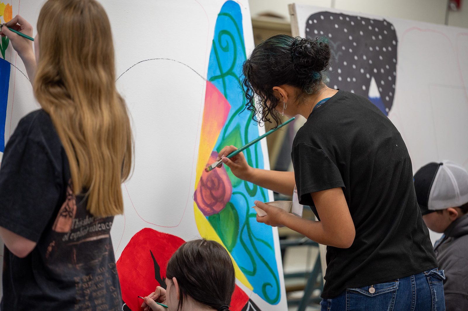 Students painting on an interior mural