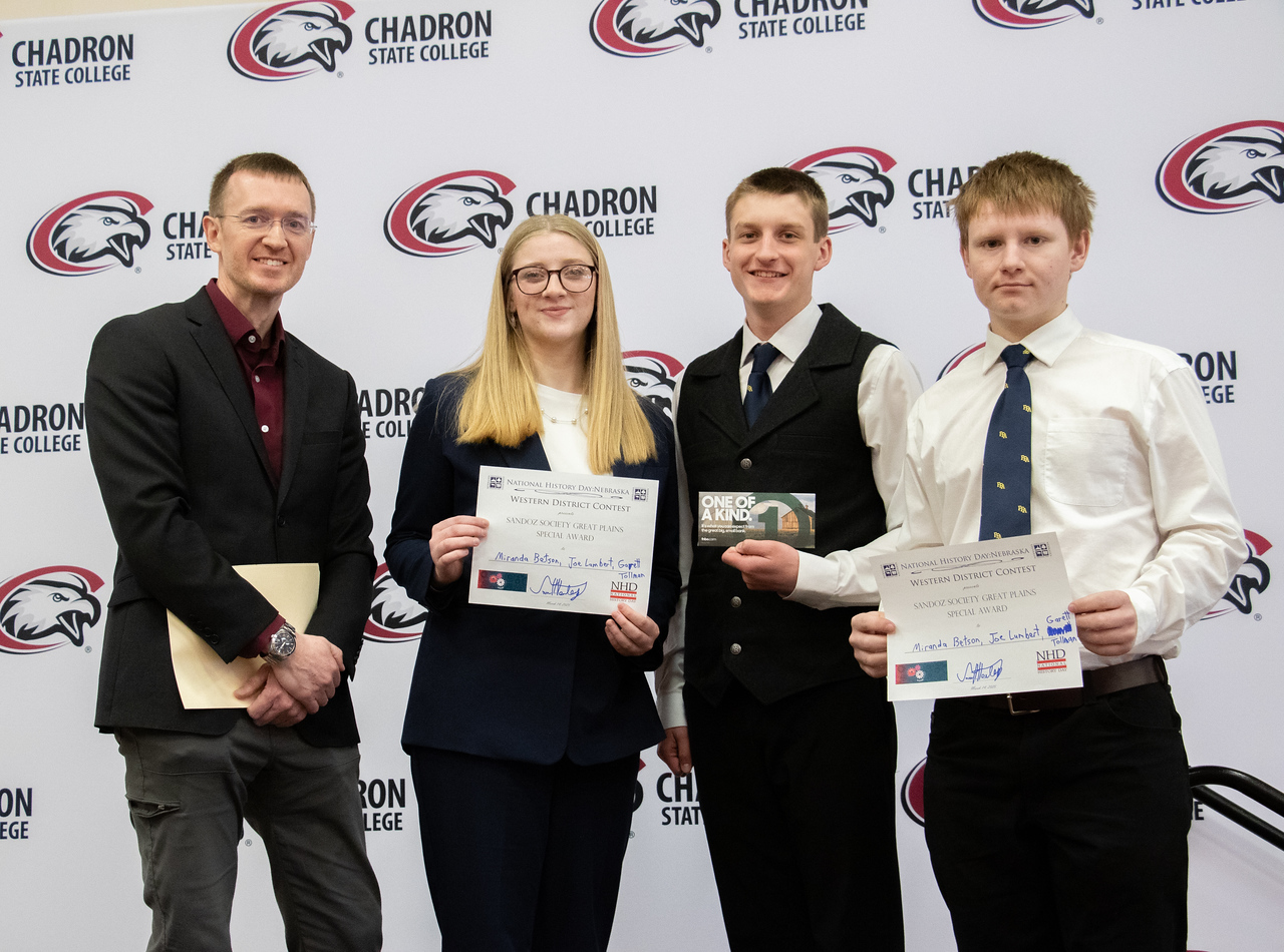 Three students with awards and a professor