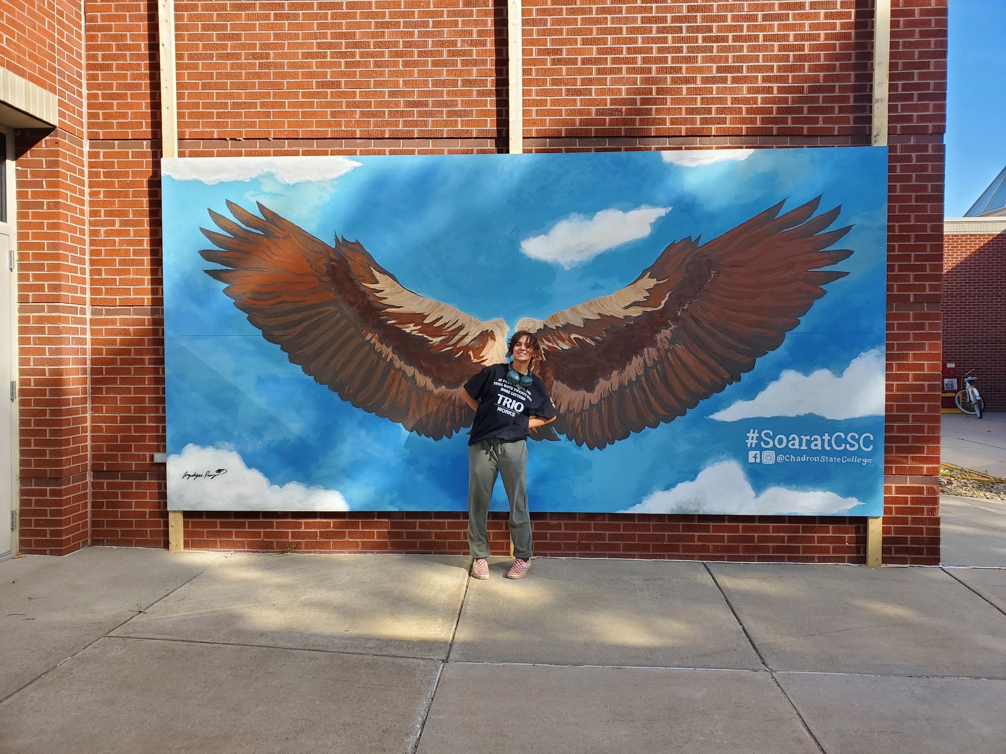 Student standing by eagle mural