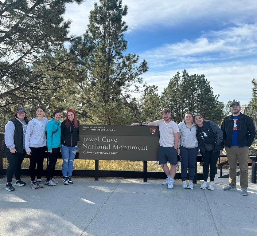 Students standing by a cave sign