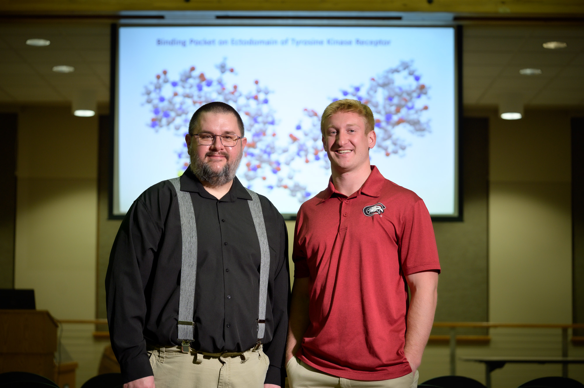 A faculty member and student pose at a presentation