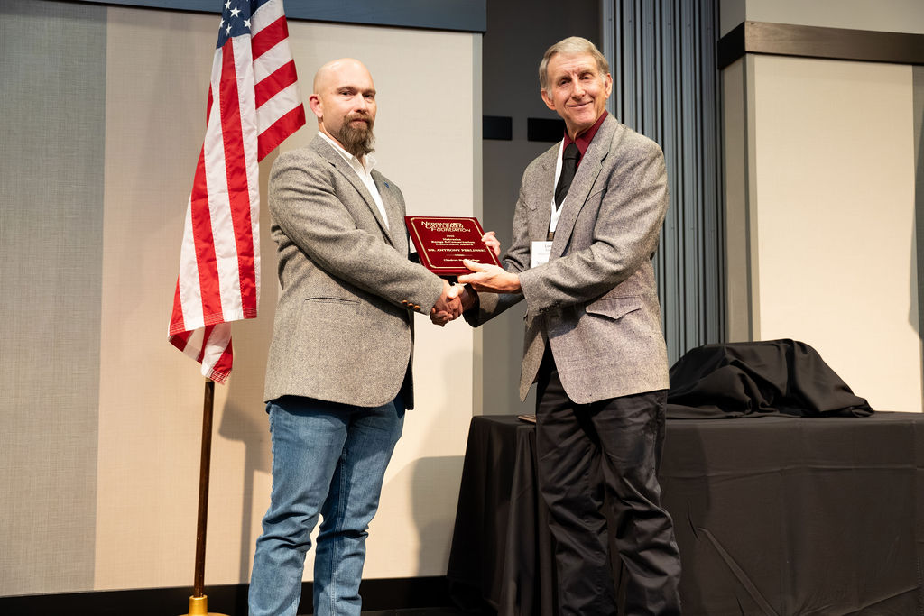 Two men on a stage with an award
