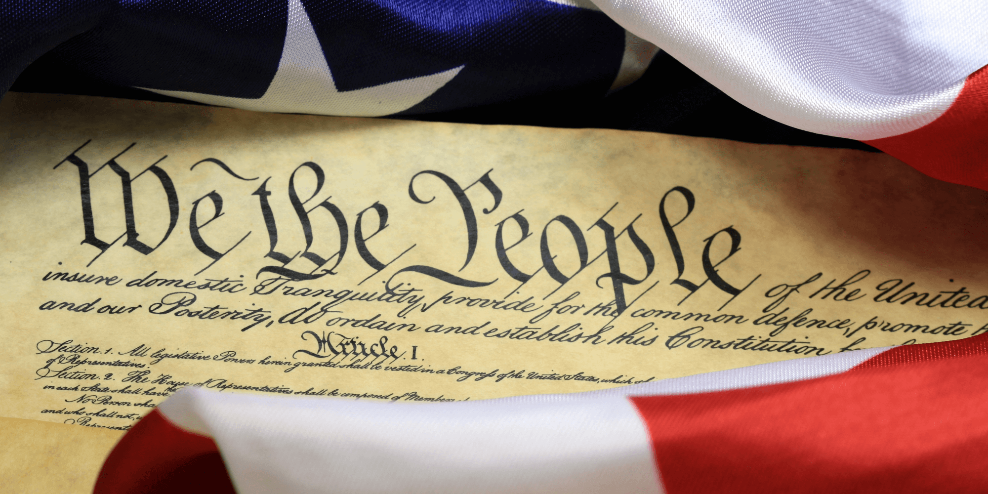 Closeup view of the opening text to the United States Constitution framed by the United States flag