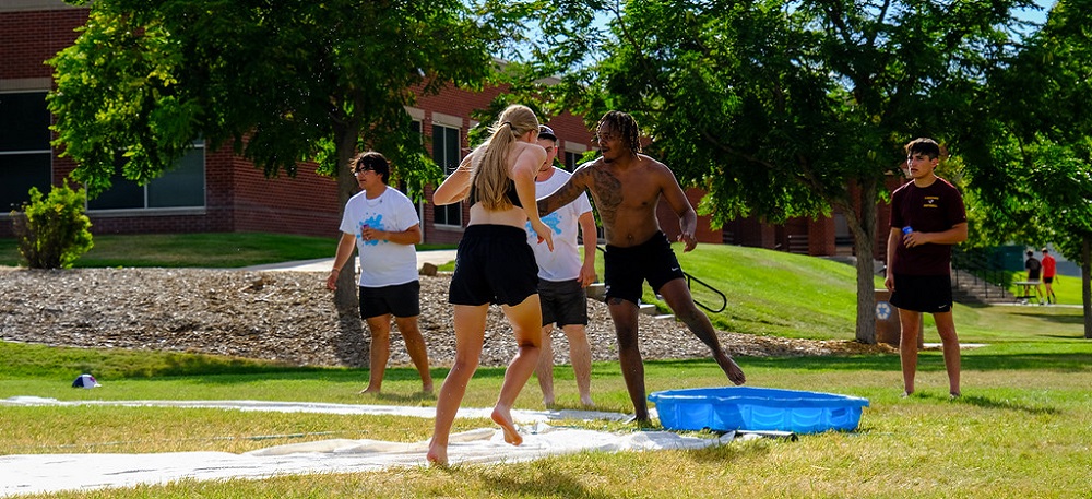Students playing slip and slide whiffle ball