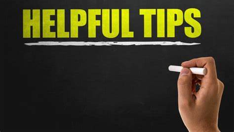 Yellow letters spelling Helpful Tips on Chalkboard. White chalk line underlining the words. Hand holding white chalk towards chalkboard.