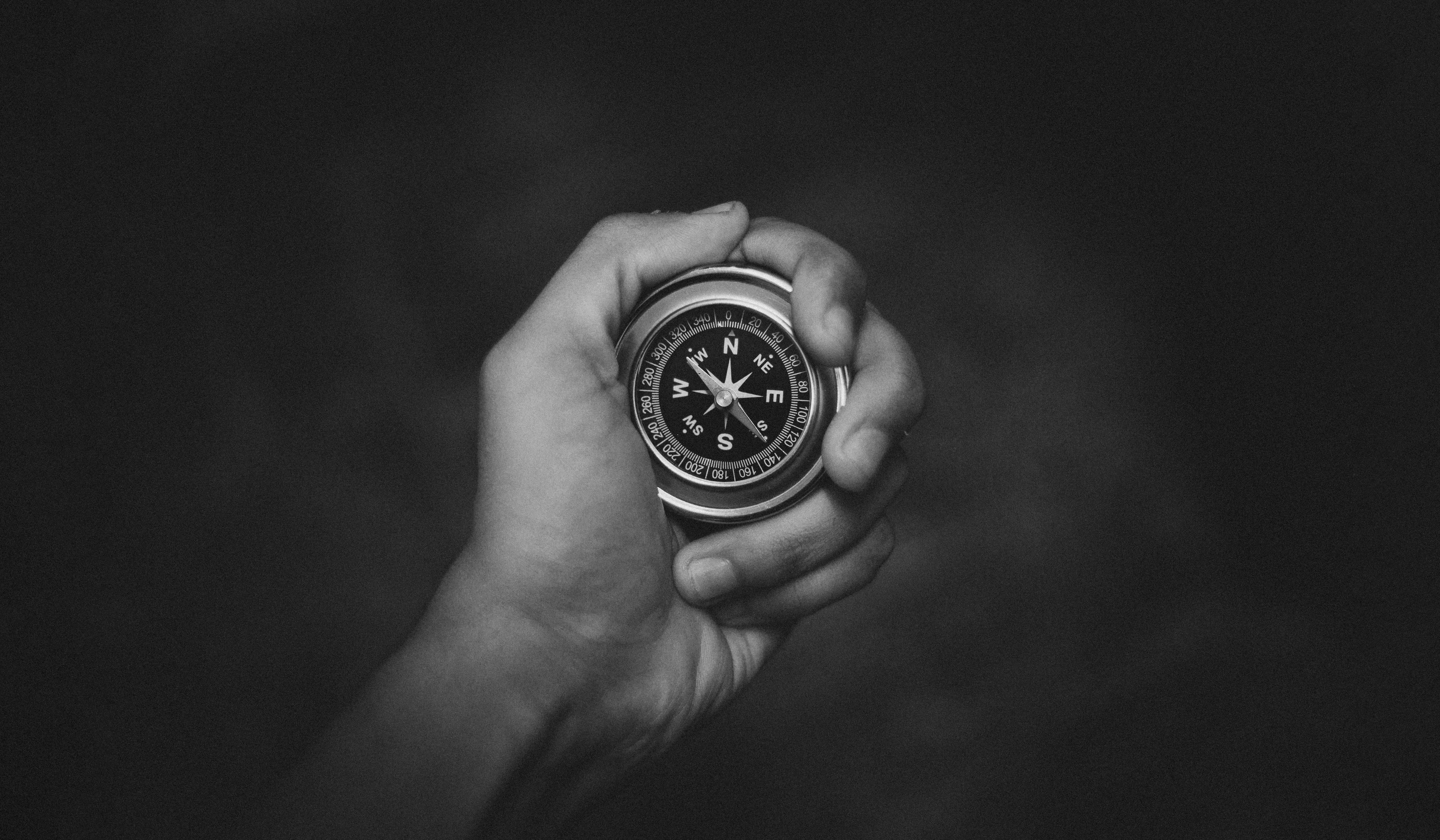 Hand holding round analog compass