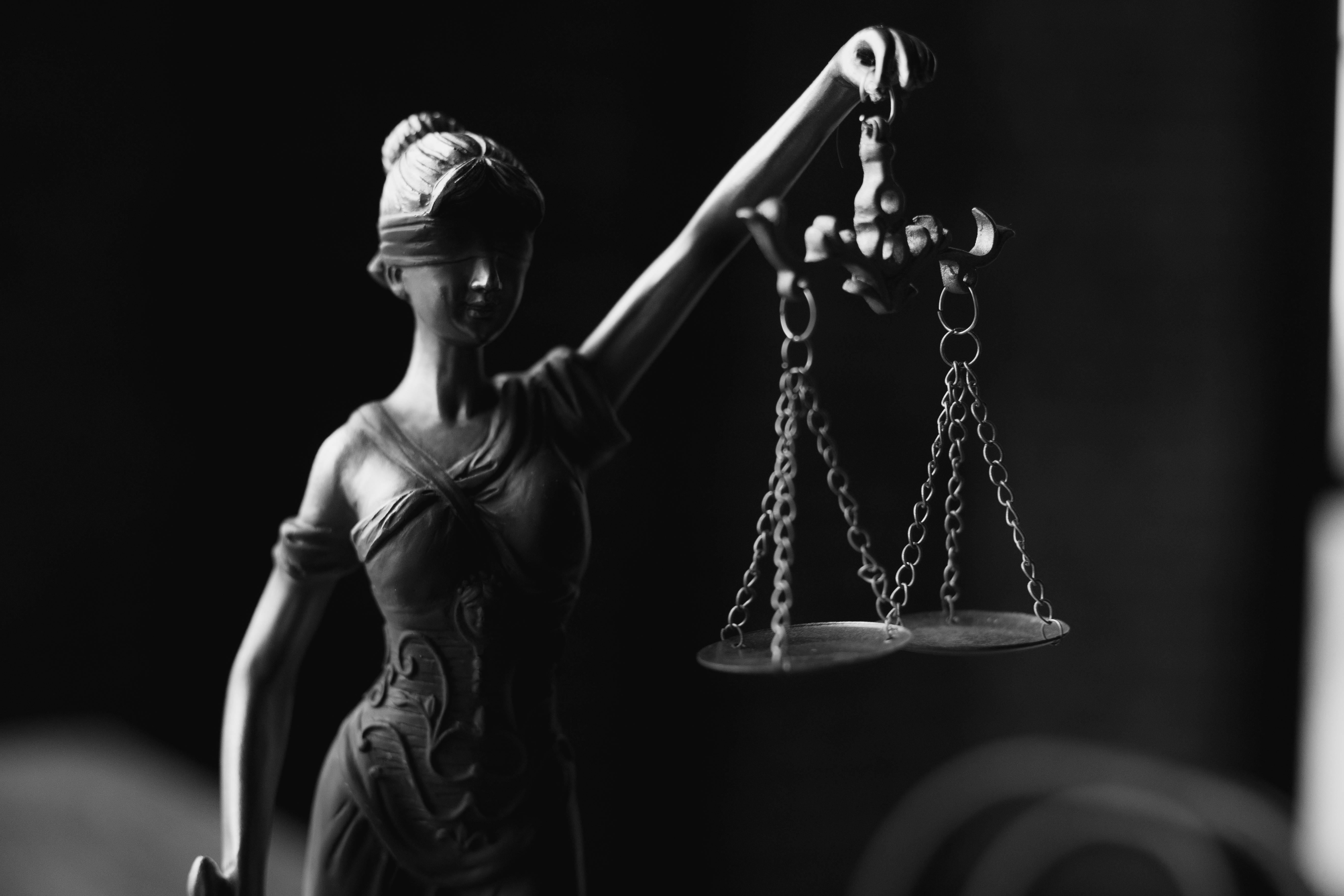 Statue of Lady Justice holding up balanced scales.
